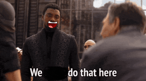A Man In A Suit Says We Do That Here In Front Of A Group Of People GIF