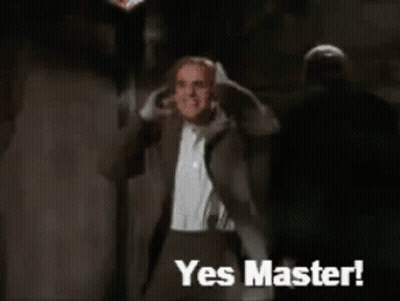A Man In A Suit Says Yes Master In Front Of A Monster GIF