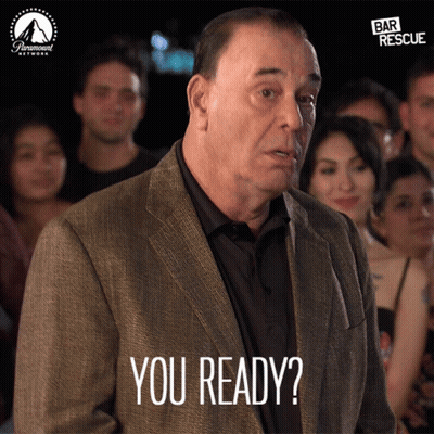 A Man In A Suit Says You Ready In Front Of A Crowd Of People GIF