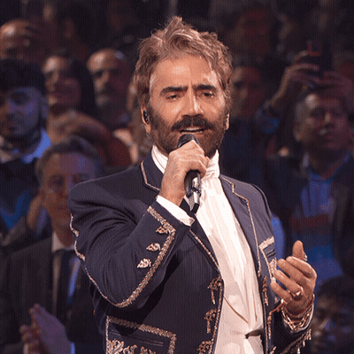 A Man In A Suit Singing Into A Microphone GIF