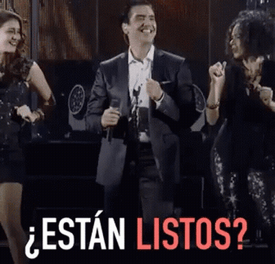 A Man In A Suit Singing Into A Microphone With The Words " Estan Listos " In Red GIF