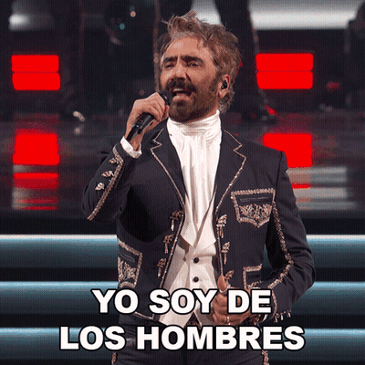 A Man In A Suit Singing Into A Microphone With Yo Soy De Los Hombres Below Him GIF