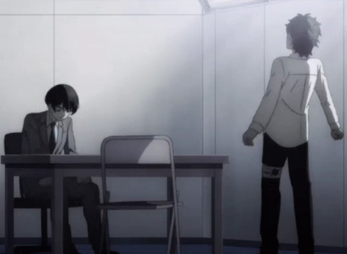 A Man In A Suit Sits At A Desk While Another Man Stands In Front Of Him GIF