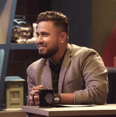A Man In A Suit Sits At A Table With A Coffee Mug That Says ' Son Of A Bitch ' On It GIF