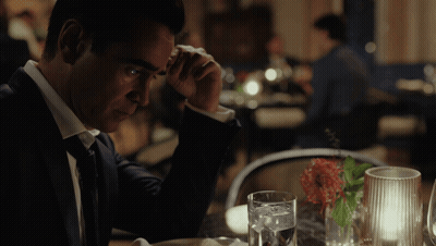 A Man In A Suit Sits At A Table With A Glass Of Water On It GIF