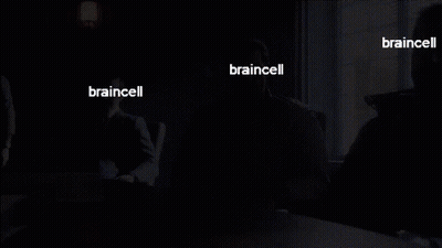 A Man In A Suit Sits At A Table With The Words Braincell On His Face GIF