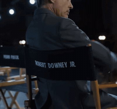 A Man In A Suit Sits In A Director 'S Chair With Pedro Pascal Jr. Written On The Back GIF
