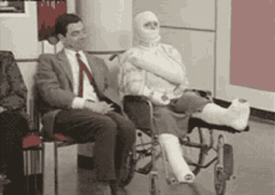 A Man In A Suit Sits Next To A Woman In A Wheelchair With A Cast On Her Leg . GIF