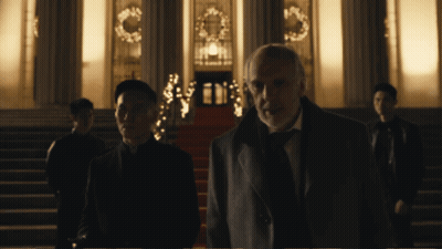 A Man In A Suit Stands In Front Of A Building GIF