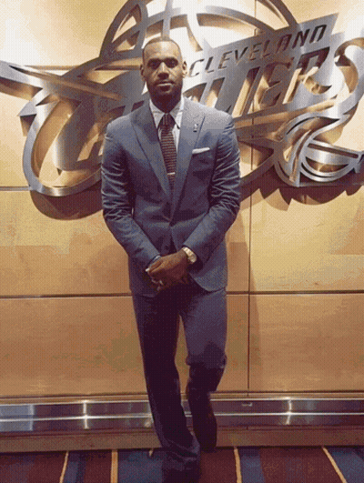 A Man In A Suit Stands In Front Of A Cleveland Thunder Sign GIF