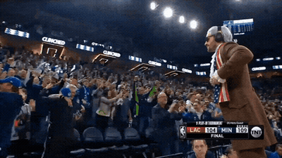 A Man In A Suit Stands In Front Of A Crowd At A Basketball Game With The Score Lac 104 Min 109 GIF