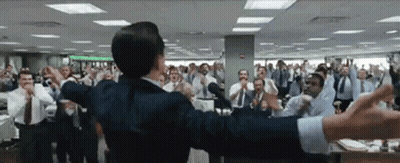 A Man In A Suit Stands In Front Of A Crowd Of People GIF