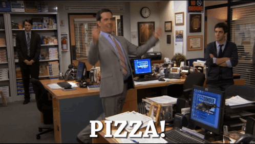 A Man In A Suit Stands In Front Of A Desk That Says Pizza On It GIF