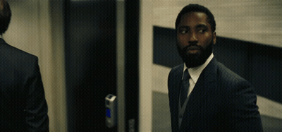A Man In A Suit Stands In Front Of A Door GIF