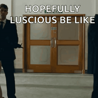 A Man In A Suit Stands In Front Of A Door That Says Hopefully Luscious Be Like On It GIF