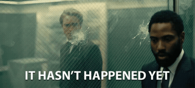 A Man In A Suit Stands In Front Of A Glass Wall With The Words " It Hasn 'T Happened Yet " Below Him GIF