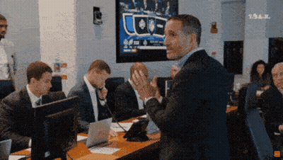 A Man In A Suit Stands In Front Of A Group Of People In Front Of A Screen That Says Tnt GIF