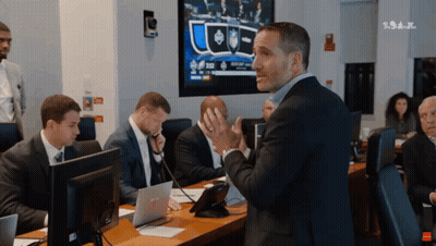 A Man In A Suit Stands In Front Of A Group Of People In Front Of A Screen That Says ' Tsn ' GIF