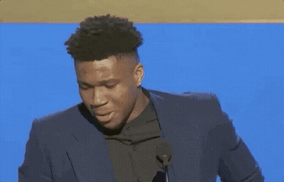 A Man In A Suit Stands In Front Of A Microphone GIF