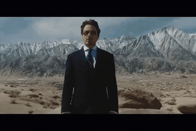 A Man In A Suit Stands In Front Of A Mountain Range GIF