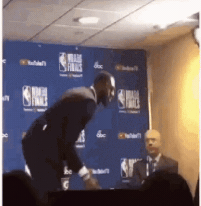 A Man In A Suit Stands In Front Of A Nba Finals Backdrop GIF