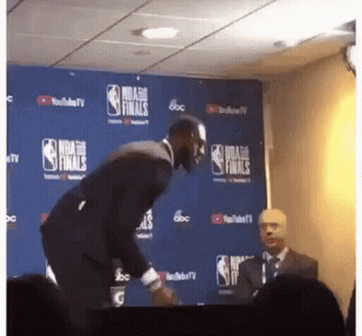 A Man In A Suit Stands In Front Of A Nba Finals Sign GIF