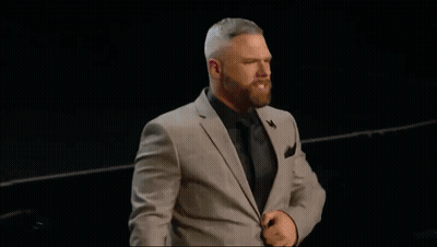 A Man In A Suit Stands In Front Of A Pink Shirt GIF