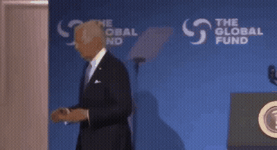 A Man In A Suit Stands In Front Of A Podium That Says The Global Fund On It GIF