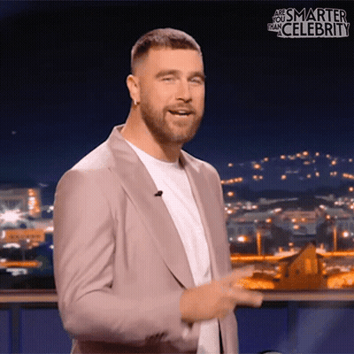 A Man In A Suit Stands In Front Of A Screen That Says " Are You Smarter Than Celebrity " GIF