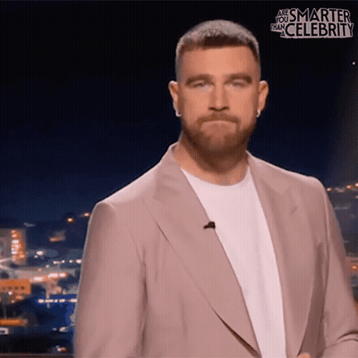 A Man In A Suit Stands In Front Of A Screen That Says " Are You Smarter Than Celebrity " GIF