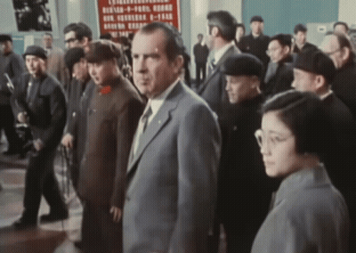 A Man In A Suit Stands In Front Of A Sign That Says ' Chinese ' On It GIF
