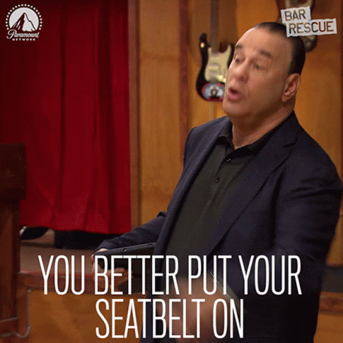 A Man In A Suit Stands In Front Of A Sign That Says " You Better Put Your Seatbelt On " GIF