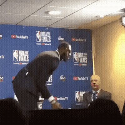 A Man In A Suit Stands In Front Of A Wall That Says Nba Finals On It GIF