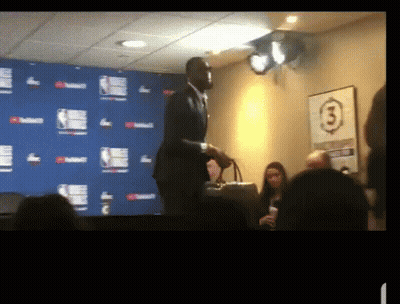 A Man In A Suit Stands In Front Of A Wall With The Number 3 GIF