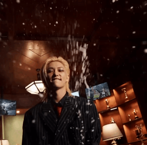 A Man In A Suit Stands In Front Of A Wall With Trophies GIF