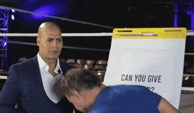 A Man In A Suit Stands In Front Of A White Board That Says Can You Give GIF