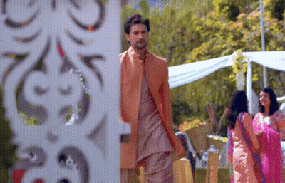 A Man In A Suit Stands In Front Of A White Wall GIF