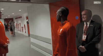 A Man In A Suit Stands Next To A Man In A Red Shirt That Says Lfc Tv GIF