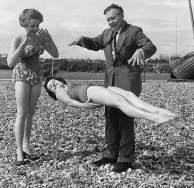 A Man In A Suit Stands Next To A Woman In A Bikini GIF