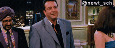 A Man In A Suit Stands Next To A Woman In A Blue Dress And A Man In A Turban GIF
