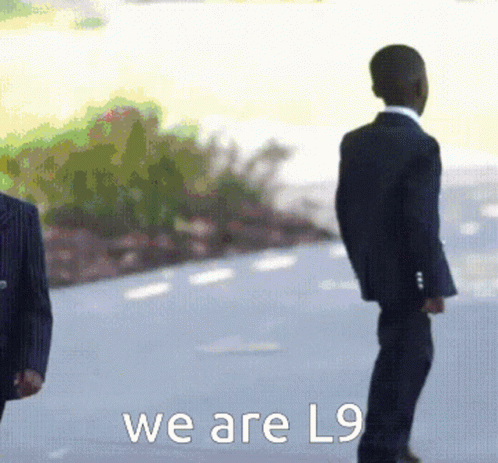 A Man In A Suit Stands Next To Another Man In A Suit With The Words We Are L9 Below Them GIF