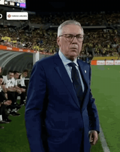 A Man In A Suit Stands On A Soccer Field GIF