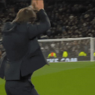 A Man In A Suit Stands On A Soccer Field In Front Of A Heineken Ad GIF