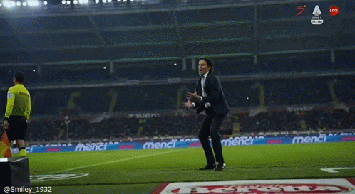 A Man In A Suit Stands On A Soccer Field GIF