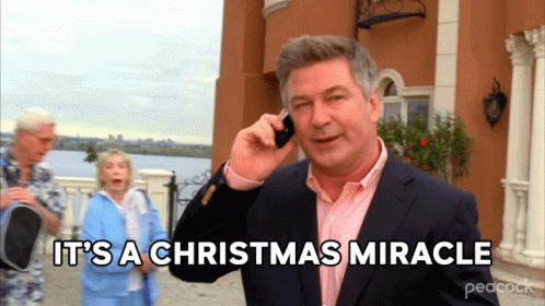 A Man In A Suit Talking On A Cell Phone With The Words It 'S A Christmas Miracle Behind Him GIF