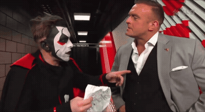 A Man In A Suit Talks To A Man In A Clown Mask GIF