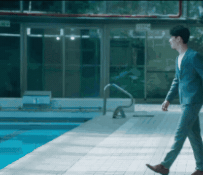 A Man In A Suit Walks By A Pool GIF