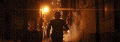 A Man In A Suit Walks Down A Dark Alley At Night GIF