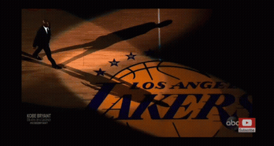 A Man In A Suit Walks On A Basketball Court With The Los Angeles Lakers Logo In The Background GIF