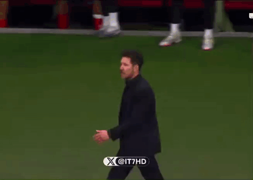A Man In A Suit Walks On A Soccer Field With A X @ It7hd Logo In The Corner GIF